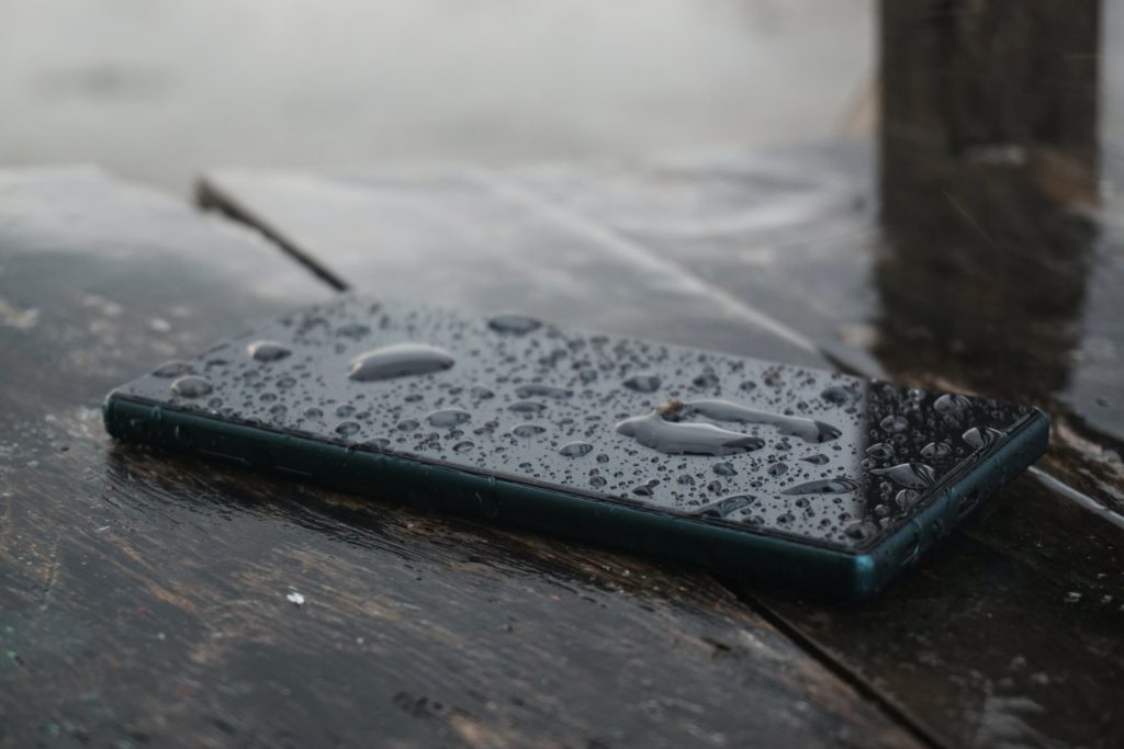 black smartphone on top of brown wooden surface