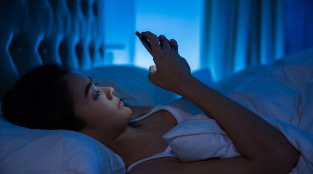 a woman using phone in bed in blue light