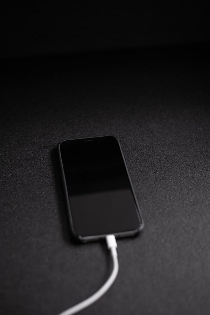 black smartphone charging on table